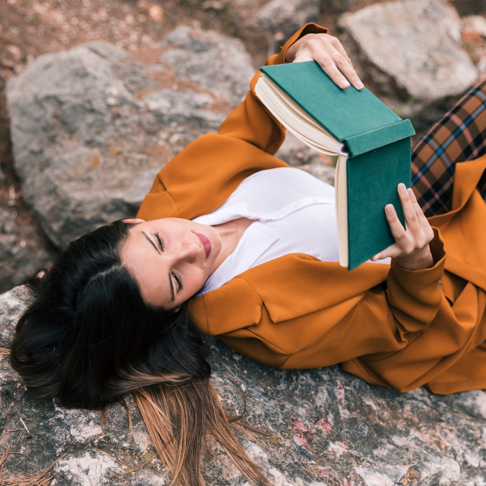 una-vista-aerea-de-una-mujer-joven-acostada-en-el-libro-de-lectura-de-la-roca